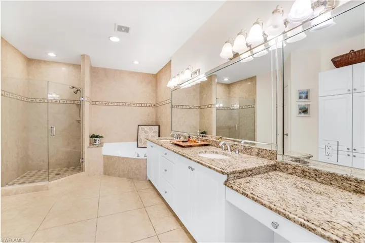 Bathroom featuring tile floors, dual sinks and vanity, soaking tub and walk in shower