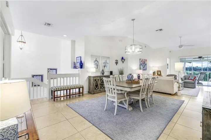 Dining room and living room featuring ceiling fan with notable chandelier, floors, and high vaulted ceiling