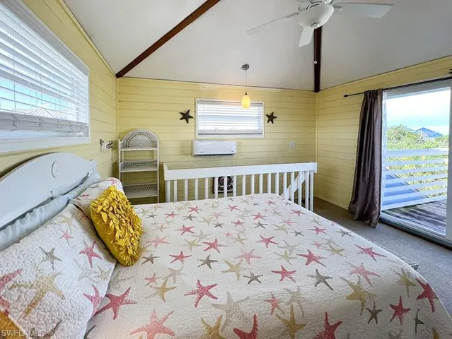 Carpeted bedroom featuring multiple windows, ceiling fan, and lofted ceiling