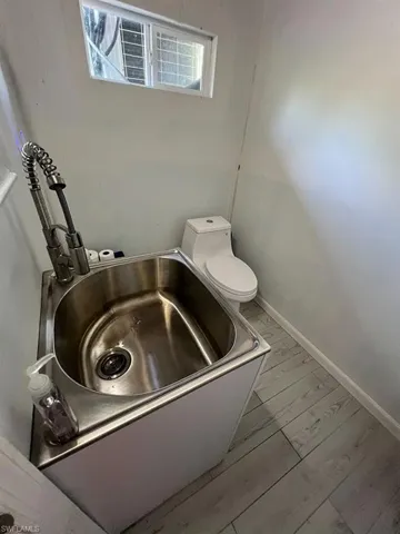 Bathroom with a bath, hardwood / wood-style flooring, and toilet