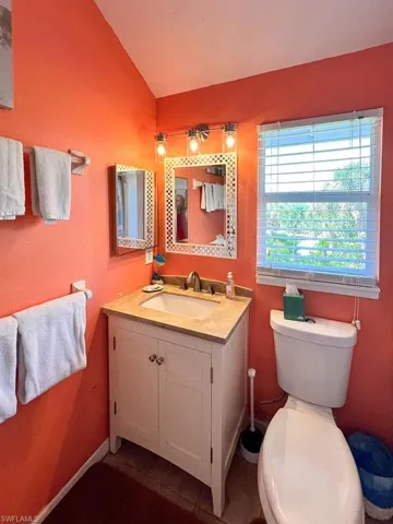 Bathroom featuring tile patterned flooring, vaulted ceiling, toilet, and vanity