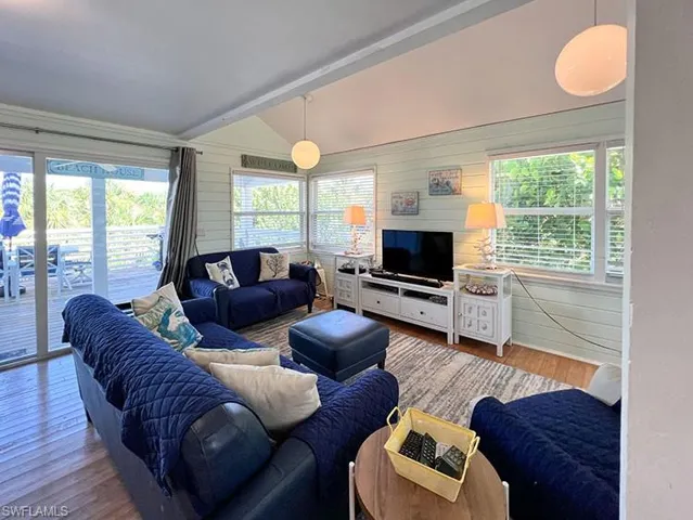 Living room with lofted ceiling with beams and hardwood / wood-style floors