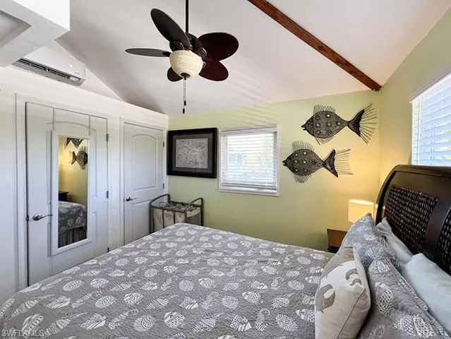 Bedroom with an AC wall unit, vaulted ceiling with beams, and ceiling fan