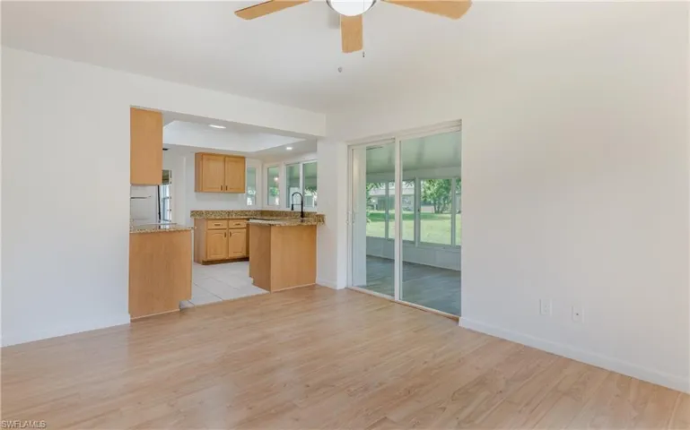Kitchen featuring a ceiling fan, light wood-type flooring, light stone counters, and a tray ceiling