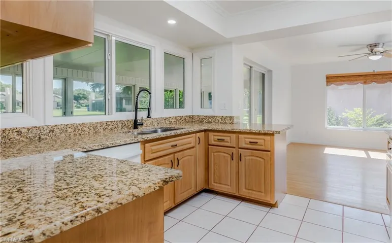 Kitchen with light stone countertops, a ceiling fan, recessed lighting, light tile patterned floors, and a peninsula
