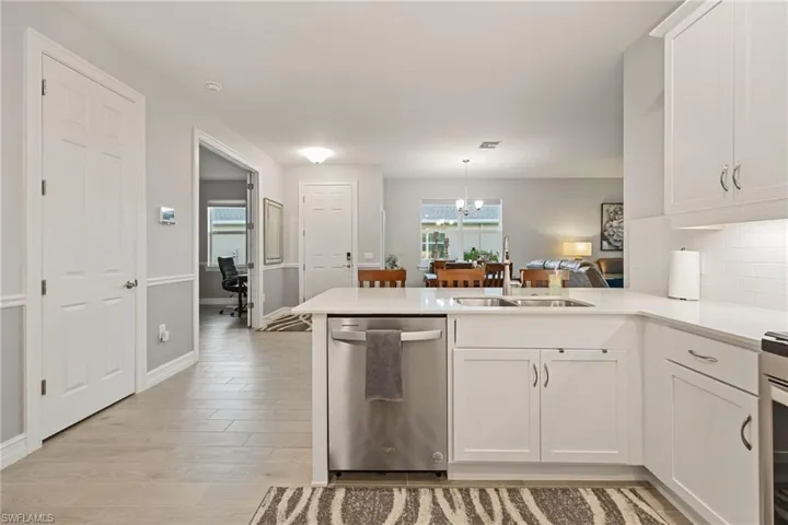 Kitchen featuring white cabinets, stainless steel dishwasher, a peninsula, and a chandelier