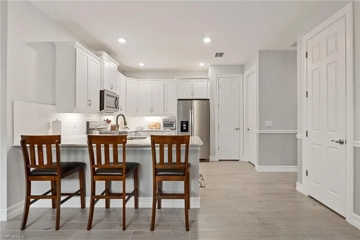Kitchen featuring white cabinets, appliances with stainless steel finishes, backsplash, a peninsula, and recessed lighting