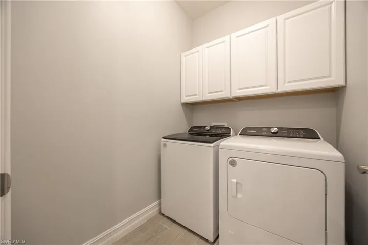 Laundry room featuring cabinet space, wood tiled floors, and washing machine and dryer