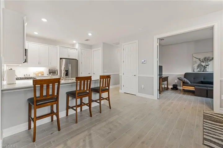 Kitchen with a peninsula, white cabinetry, a breakfast bar area, recessed lighting, and wood tiled floors