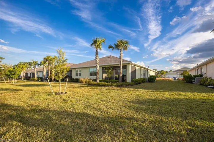 Back of house featuring a yard, a sunroom, and stucco siding