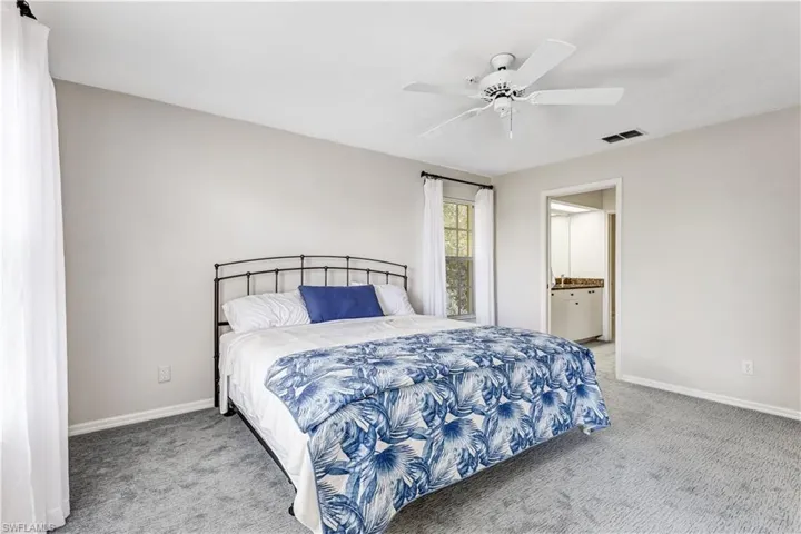 Bedroom featuring light carpet, ceiling fan, and connected bathroom