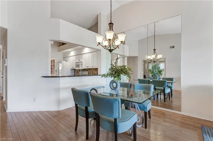 Dining area with hanging lights, vaulted ceiling, and light wood-style flooring