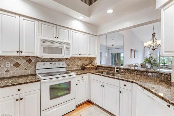 Kitchen featuring white appliances, white cabinetry, and lofted ceiling