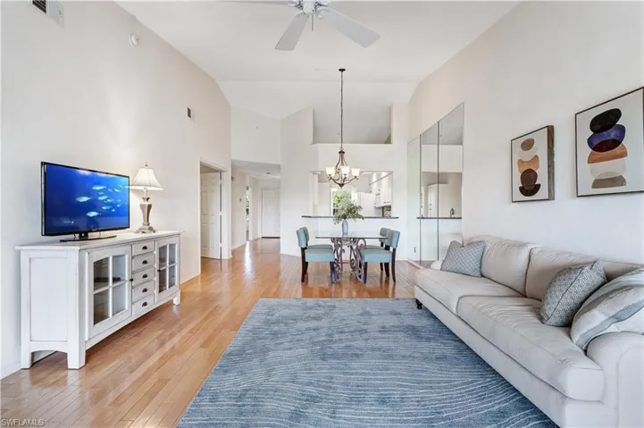 Living area featuring ceiling fan, a chandelier, lofted ceiling, and light wood finished floors