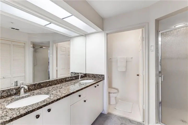 Full bath with a closet, double vanity, a stall shower, and light tile patterned floors