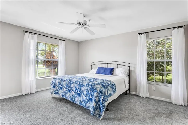 Carpeted bedroom featuring ceiling fan and baseboards