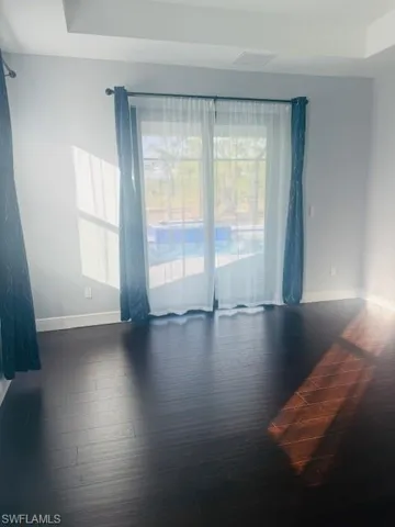 Unfurnished room with dark wood-type flooring and baseboards