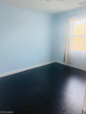Unfurnished room with dark wood-style floors and ceiling fan