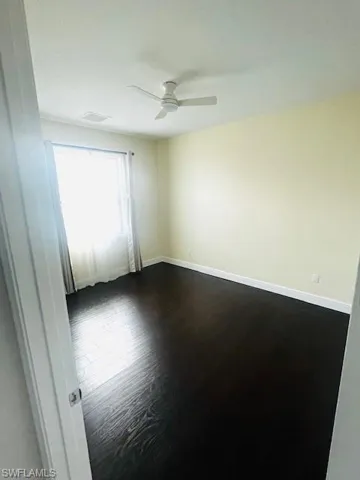 Unfurnished room with dark wood-style floors and ceiling fan