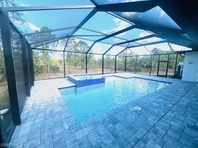 View of pool featuring a sunroom, a patio area, a lanai, and a pool with connected hot tub