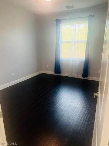 Empty room with baseboards and dark wood-style floors