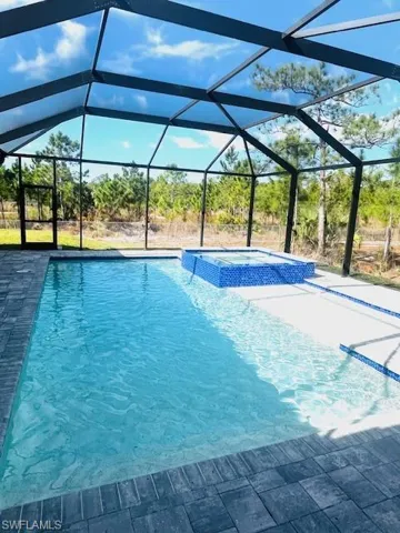 View of pool featuring a lanai, a sunroom, and a pool with connected hot tub