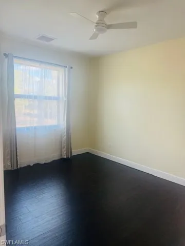 Empty room with dark wood-style flooring and a ceiling fan
