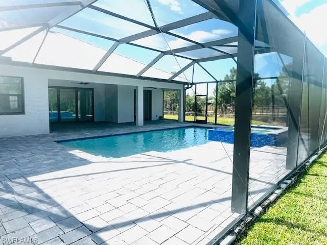View of pool with a sunroom, a patio area, glass enclosure, and a pool with connected hot tub