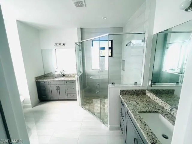 Bathroom featuring two vanities, a stall shower, and a freestanding tub