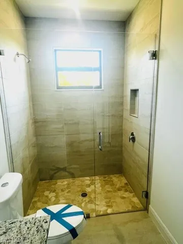 Full bathroom featuring toilet and a shower stall