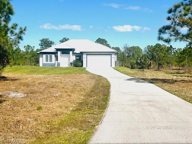 View of front facade featuring driveway, a garage, and a front lawn