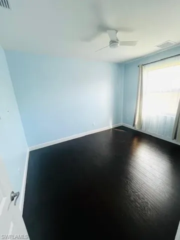 Empty room featuring dark wood-type flooring and ceiling fan