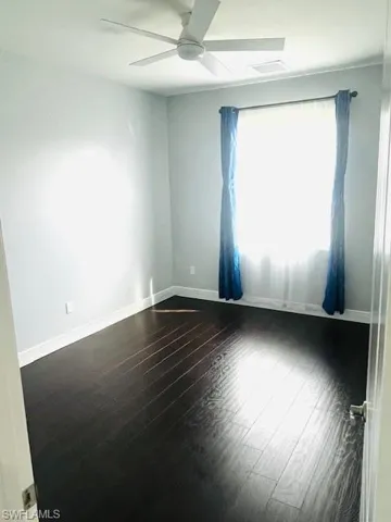 Empty room featuring dark wood-style floors and ceiling fan