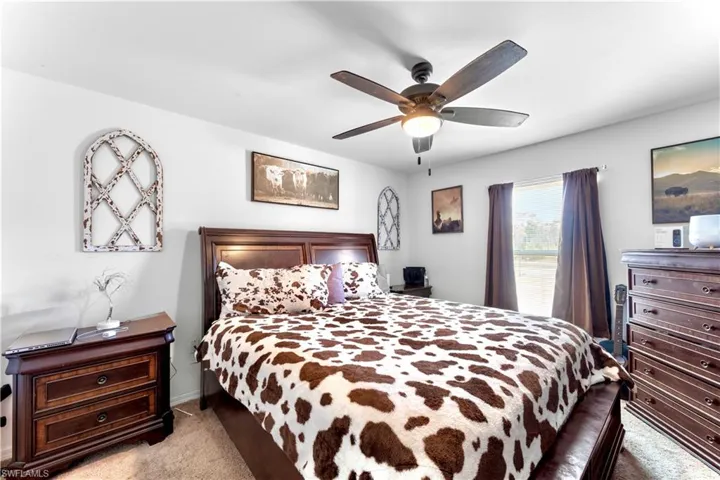 Carpeted bedroom featuring ceiling fan