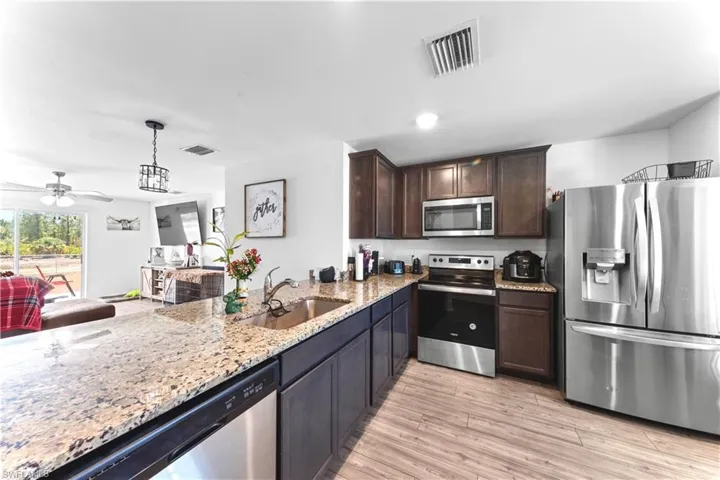 Kitchen with stainless steel appliances, dark brown cabinetry, visible vents, and a sink