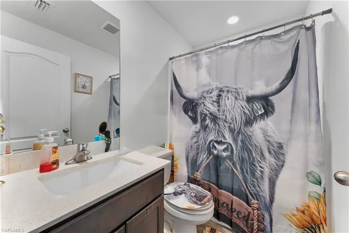 Bathroom featuring toilet, visible vents, curtained shower, and vanity