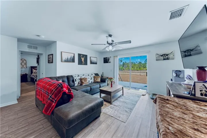 Living room featuring ceiling fan, visible vents, and wood finished floors