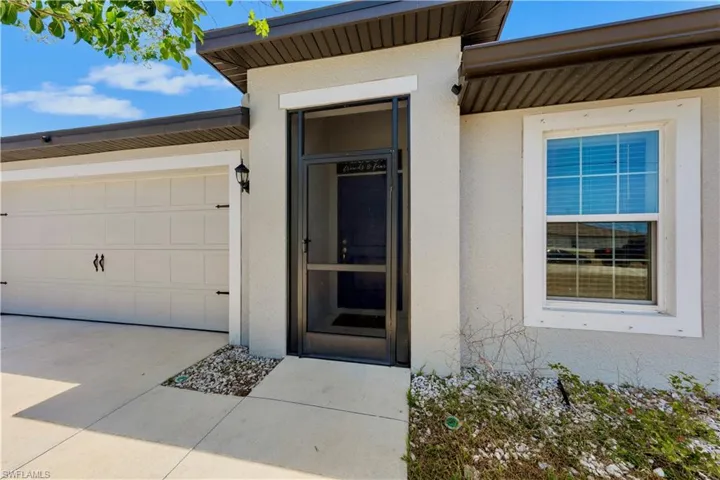 Entrance to property with stucco siding, an attached garage, and driveway