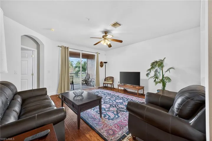 Living area with wood finished floors, a ceiling fan, and arched walkways