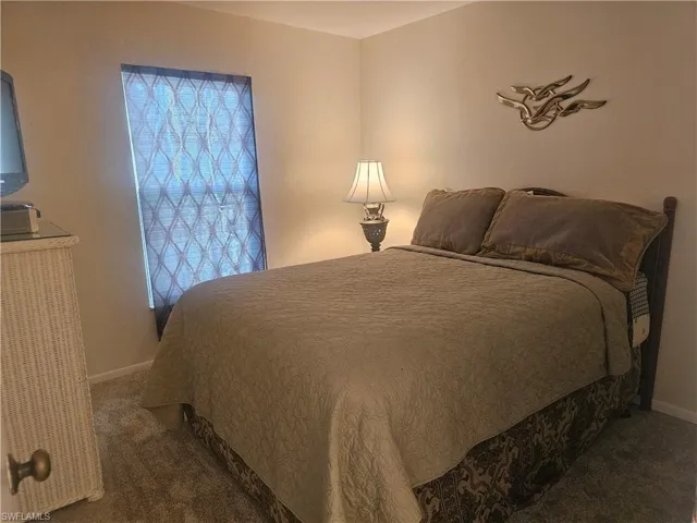 Guest Bedroom featuring  window onto front balcony towards gulf beach, neutral carpet flooring, closet and hall to guest full bath and laundry.