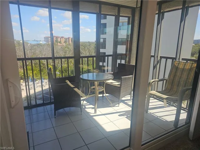 Bright corner screened lanai with tiled floors, impact sliders, storm shutters, and just enough shade to create a relaxed space to unwind after a day at the beach.