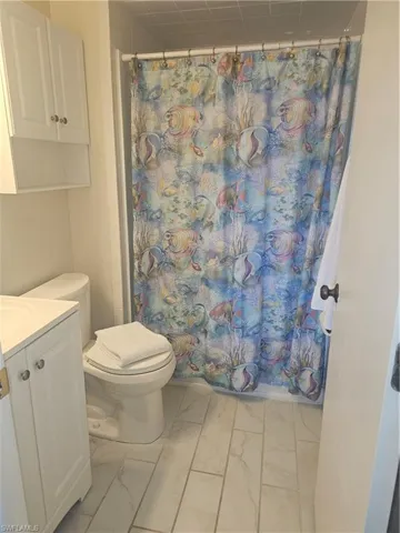Full bath with vanity and light marble finish flooring