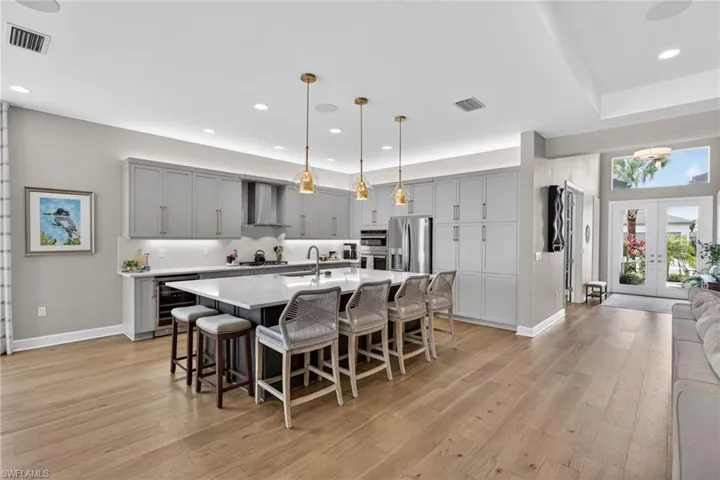 Spacious kitchen featuring a large central island with seating, light gray cabinetry, and stainless steel appliances