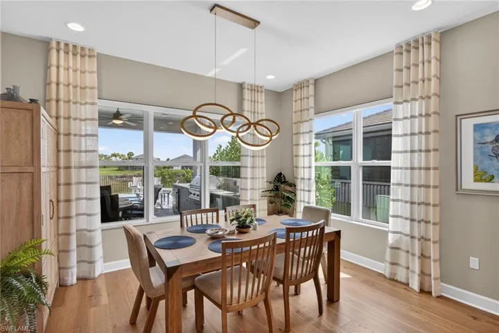 Dining area featuring wood-finish flooring, a modern chandelier with circular lighting, and recessed ceiling lights