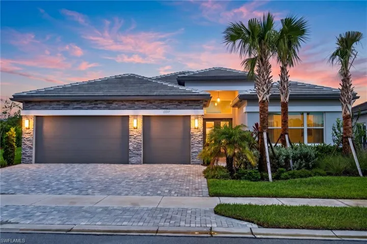 Contemporary facade featuring a stone veneer accent, paver driveway, and a tile roof