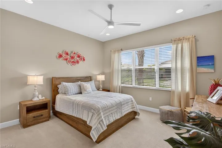 Carpeted bedroom featuring a large window with blinds, a ceiling fan with integrated lighting, and recessed lighting