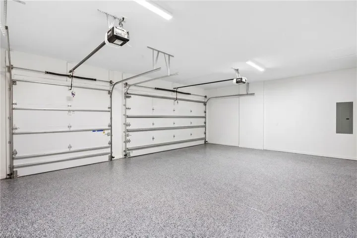 Spacious garage featuring two overhead doors with automatic openers, a speckled epoxy floor finish, and ample overhead lighting