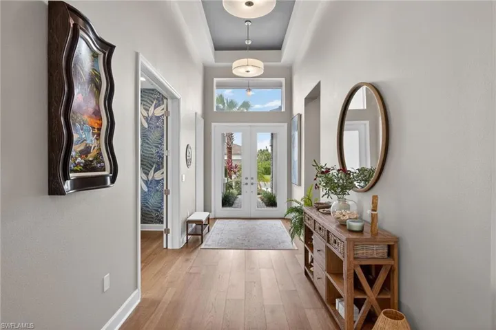 Foyer featuring double entry doors, transom windows, wood-finish flooring, and a tray ceiling with recessed lighting