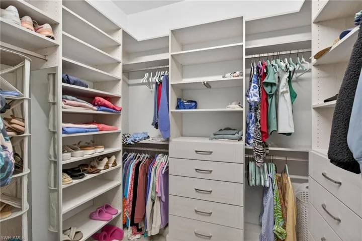 Custom closet system featuring extensive shelving, multiple hanging rods, built-in drawers with modern hardware, and dedicated shoe storage