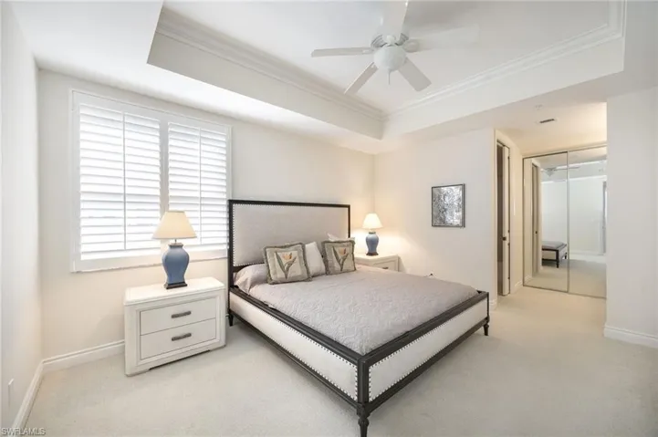Bedroom featuring ornamental molding, a closet, a tray ceiling, and light carpet